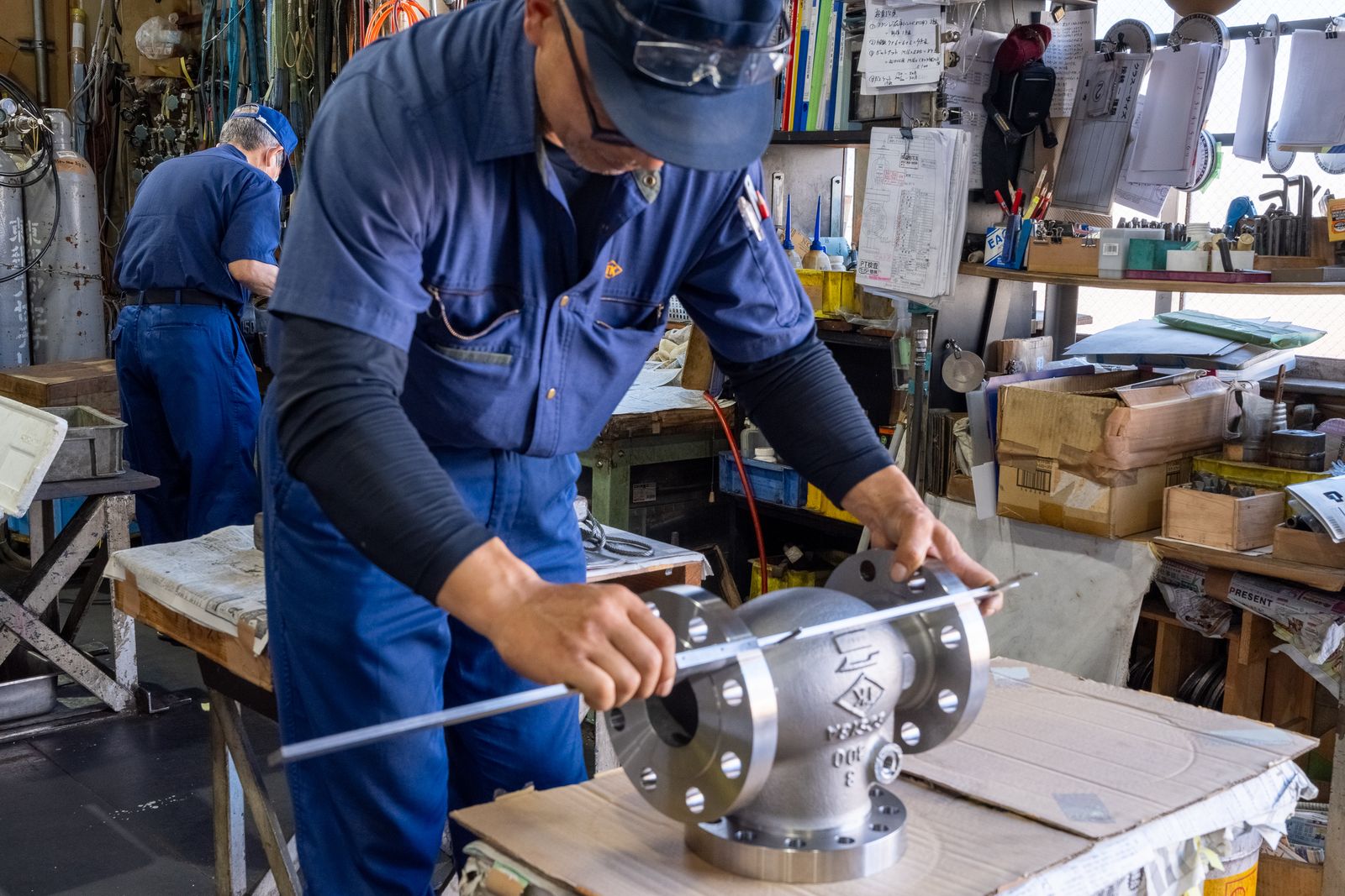 弁箱の面間を測る。奥では別の技術者が作業中